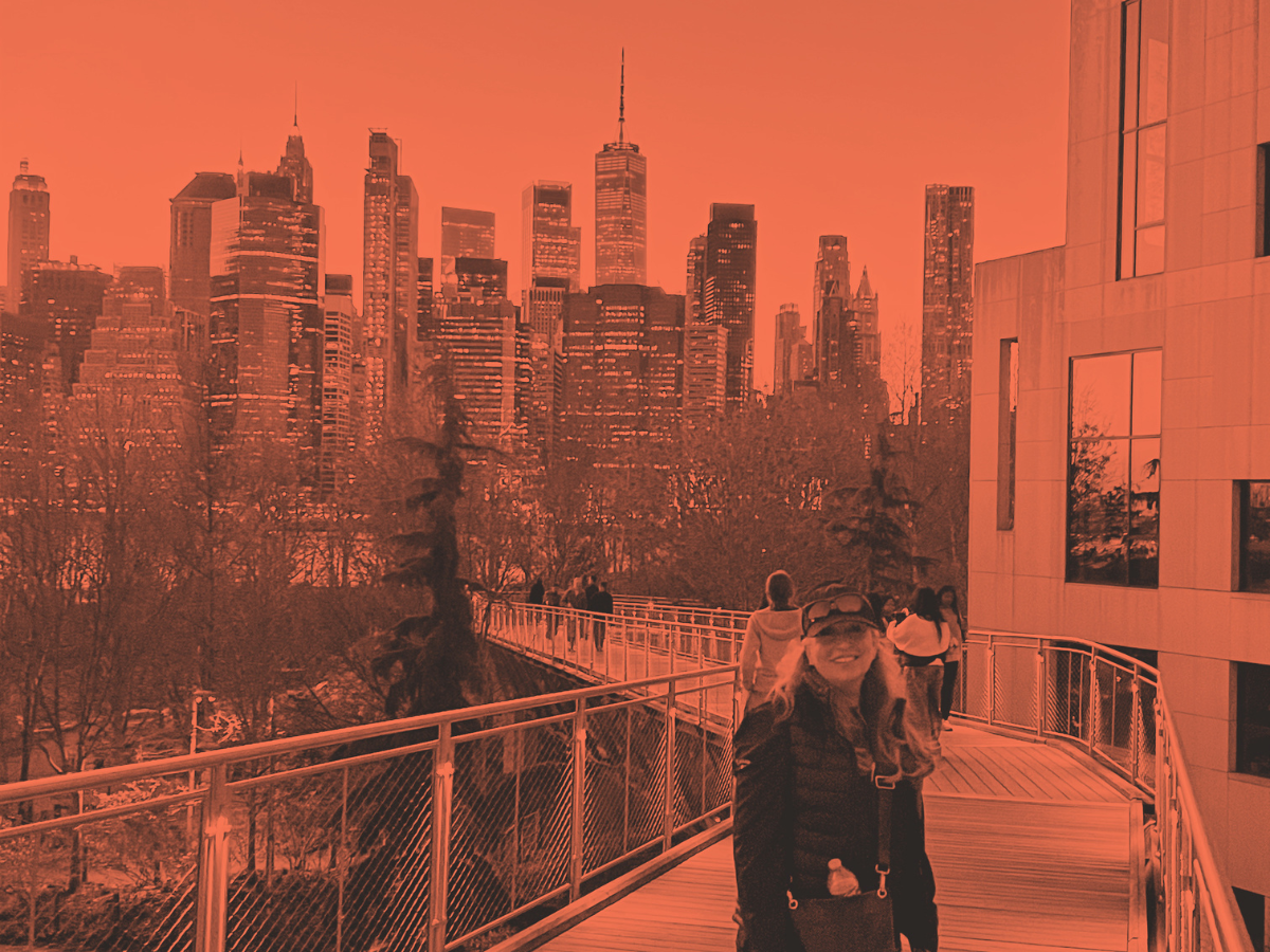 View of the New York City skyline from the High Line walkway with people walking and a woman in the foreground