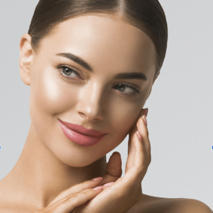 A young woman with a glowing complexion smiles softly, embodying the essence of brand growth. She has smooth skin, light makeup with pink lipstick, and her hair is neatly pulled back. One hand gently touches her face, and the background is a plain, light gray.